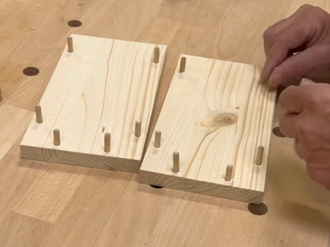 Holzdübel werden in die Löcher der 2 Leimholzplatten gegeben 