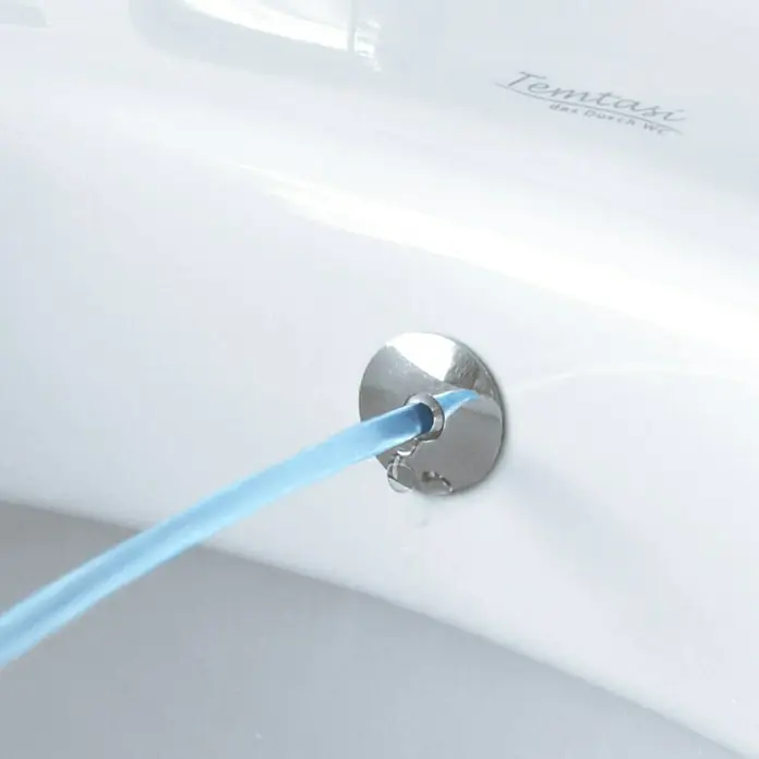 Temtasi Wand-Dusch-WC Mineral - Spülrandlos, Ohne Spezialglasur, Spülform: Tief, WC Abgang: Waagerecht, Weiß - Nahaufnahme eines Bidetaufsatzes mit blauem Wasserstrahl.
