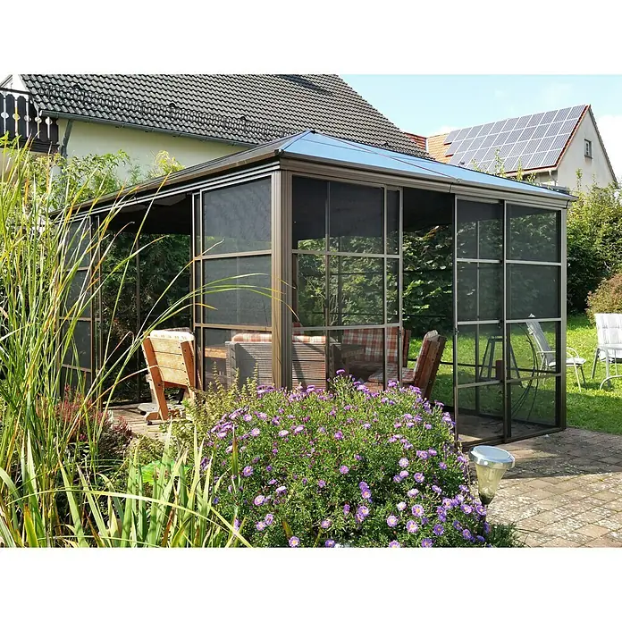 Sojag Standard-Pavillon Castel 12 x 14 - B x T: 427 x 362 cm, Farbe Gestell: Bronze, Aluminium - Das Bild zeigt einen stilvollen Pavillon mit Insektenschutz, umgeben von üppiger Vegetation und lila Blumen, ideal für entspannte Stunden im Freien.