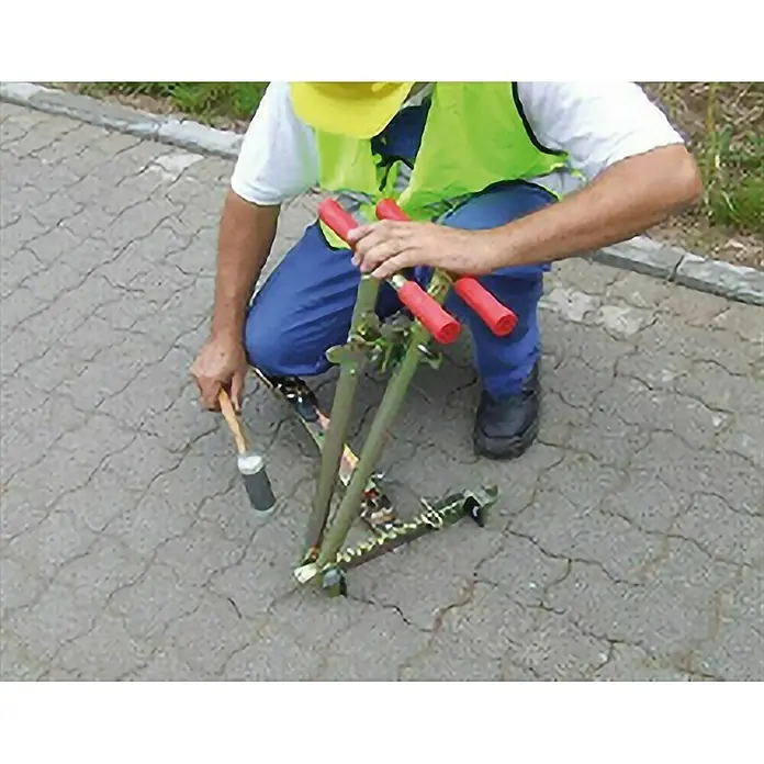 Heka Extractor de piedras - 90 mm - 270 mm - El obrero está usando una herramienta para clavar postes o marcadores en el suelo para preparar trabajos de carretera.