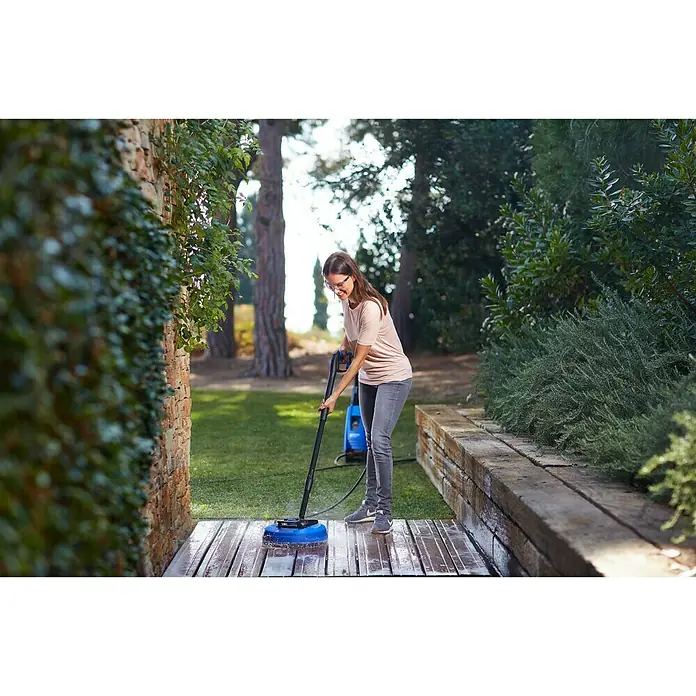 Nilfisk Hochdruckreiniger E 145.4-9 Power X-Tra - 145 bar, 2.100 W, Fördermenge: 500 l/h - Frau reinigt Terrasse mit einem Nilfisk Flächenreiniger, der mit einer Hochdruckdüse ausgestattet ist. Ideal für Terrassen und andere ebene Flächen.