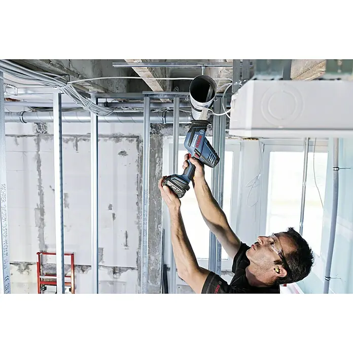 Bosch Professional AMPShare 18V Akku-Säbelsäge GSA 18 V-LI C L-Boxx18 V, Ohne Akku, 0 /min - 3.050 /min, Koffer - Ein Handwerker benutzt eine Bosch Akku-Säbelsäge, um ein Rohr an einer Deckeninstallation zu kürzen. Die Säge ist blau und hat einen schwarzen Griff.