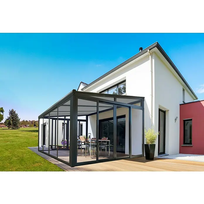 Wismar-NFI Wintergarten - 404 x 303,3 cm, Pultdach, Polycarbonat, Anthrazitgrau, Milchig Weiß - Nahaufnahme eines Wintergartens mit Glasschiebetüren und einem Essbereich, der an ein modernes Haus angebaut ist.