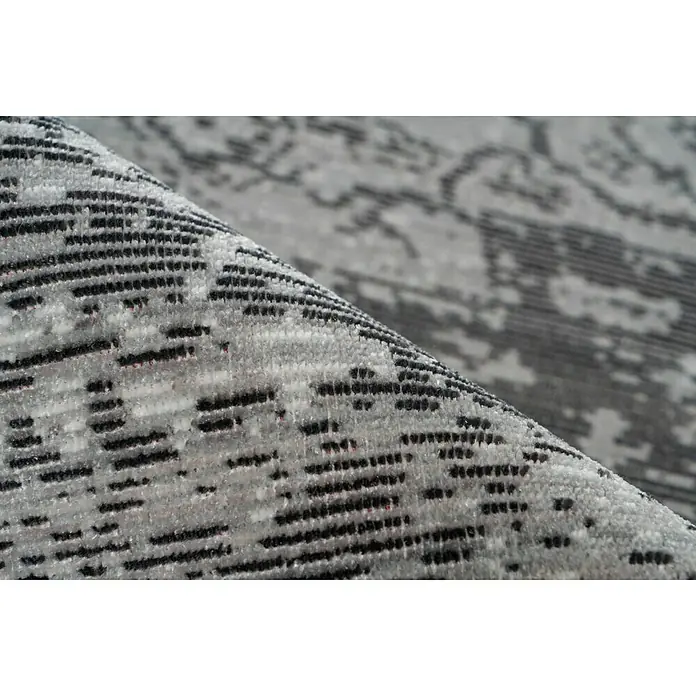 Kayoom Kurzflorteppich Baroque III - Anthrazit, 170 x 120 cm, 100 % Polyester - Nahaufnahme eines grauen Teppichs mit abstraktem Muster, der Textur und Design hervorhebt. Der Teppich ist gerollt und zeigt verschiedene Grautöne.