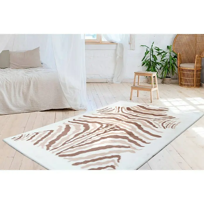 Kayoom Hochflorteppich Zebra - Weiß/Braun, 160 x 120 cm, 100 % Polyester - Ein weißer Teppich mit einem braunen Zebra-Muster liegt in einem hellen Raum und verleiht dem Zimmer einen exotischen Touch.