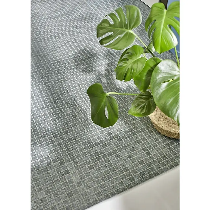 Mosaikfliese Quadrat AT 900 - 33 x 30,2 cm, Grau, Matt - Nahaufnahme des grauen Mosaikfliesenbodens, der sich diagonal erstreckt, mit einer grünen Monstera-Pflanze in der Ecke.