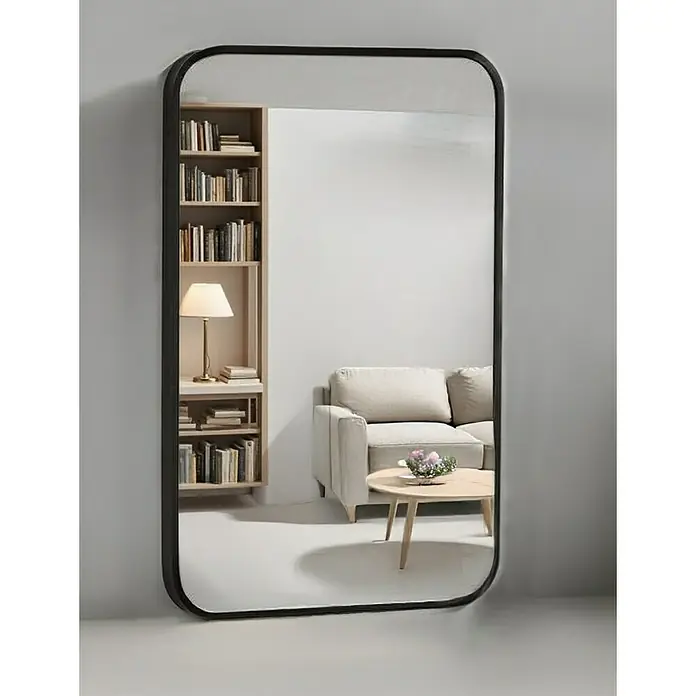 Espejo de pared Ovalado Zen - 100 x 165 cm, Negro - Un espejo de cuerpo entero con marco negro refleja una elegante sala de estar con estantería, sofá y mesa.