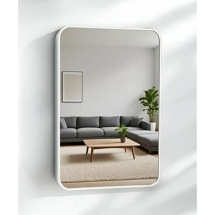 Espejo de pared Ovalado Zen - 60 x 100 cm, Blanco - Un espejo de pared rectangular con bordes redondeados y marco blanco que refleja una sala de estar con sofá, mesa y planta.