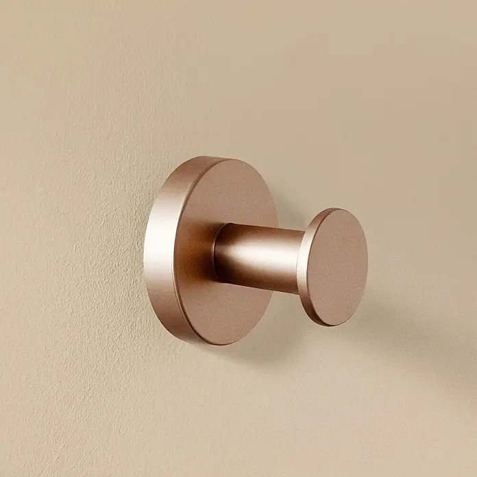 Cosmic Colgador Dual Start - Cobre, Latón, Brillante - Primer plano de un solo gancho de pared color bronce sujeto a una pared color crema.