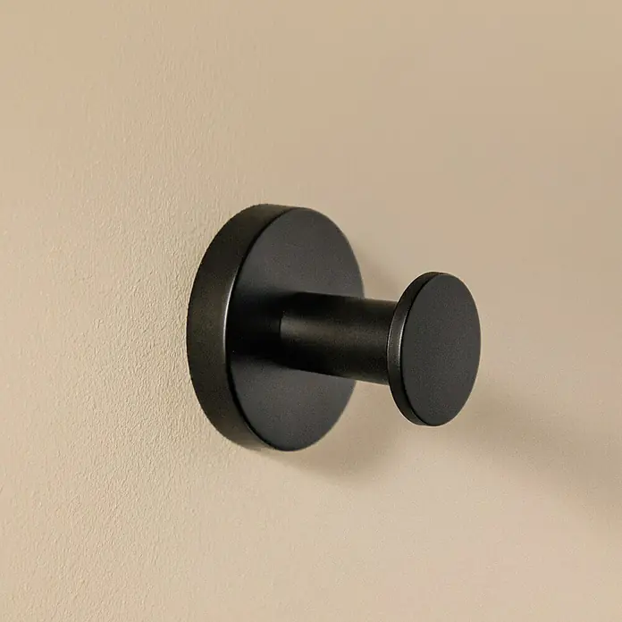 Cosmic Colgador Dual Start - Negro, Latón, Brillante - Primer plano de un colgador de abrigo negro mate individual fijado en una pared color crema.