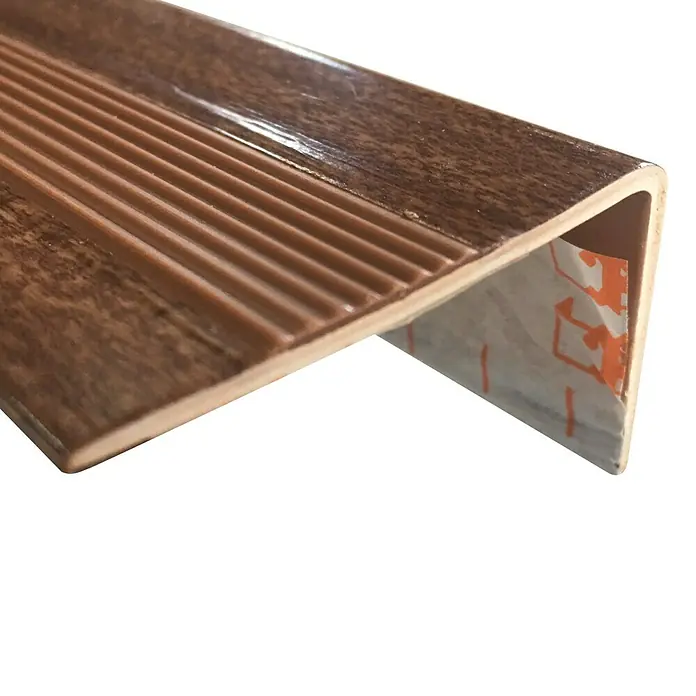 Rufete Cantonera de escalón adhesivo - 100 cm x 50 mm x 35 mm, Roble natural, Aluminio - Primer plano de un perfil de borde de escalera marrón con ranuras para mayor seguridad en escaleras.