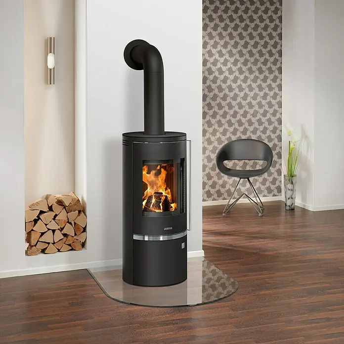 Justus Kaminofen Faro Top 2.0 - 6 kW, Raumheizvermögen: 115 m³, Abdeckung: Stahl, Schwarz - Der elegante Kaminofen mit gebogenem Glas und Holzscheit-Lager bietet Wärme und Stil für Ihr Zuhause.