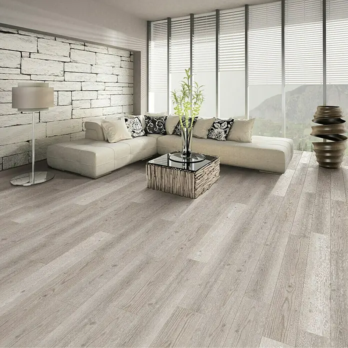Vinylboden Rigid - Kiefer Florida, Landhausdiele, 1.220 x 180 x 3,5 mm - Helles Wohnzimmer mit grauen Holzböden, Ecksofa, Fensterfront und dekorativem Couchtisch. Der Fokus liegt auf dem modernen Bodenbelag.