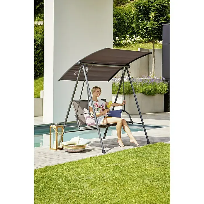 Sunfun Hollywoodschaukel - B x T x H: 164 x 132,5 x 169 cm, Stahl, Anthrazit, Neigbar (Dach) - Eine Frau entspannt sich auf einer stilvollen Gartenschaukel mit Sonnendach, ideal für sonnige Tage im Freien.