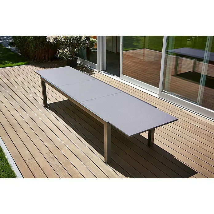 Sunfun Maja Gartentisch - L x B x H: 280 x 100 x 75 cm, Aluminium, Glas, Rechteckig, Night-Grey, Ausziehbar - Grauer Esstisch im Freien auf einer Holzterrasse. Der Tisch hat eine glatte Oberfläche und ein modernes Design, ideal für Mahlzeiten im Freien.