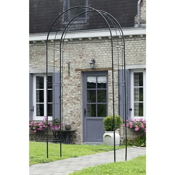 Nature Rosenbogen - 114 x 38 x 229 cm, Schwarz - Gartenbogen aus Metall vor einem Backsteinhaus.