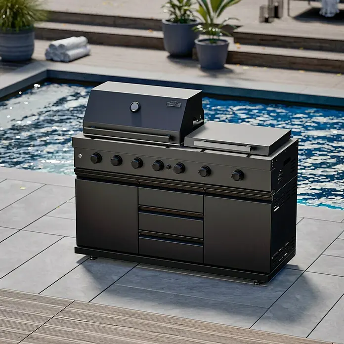 Kingstone Cube Outdoorküche - 4 -tlg., Stahl, Sintered Stone, Schwarz, Material Grillfläche: Gusseisen, Anzahl Brenner: 7 Stk. - Bild eines schwarzen Grills mit Ablagefläche im Außenbereich neben einem Pool. Der Grill verfügt über mehrere Drehknöpfe und Schrankfächer.