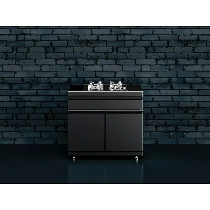 Kingstone Cube Outdoorküchen-Modul Gaskochfeld - Schwarz, B x T x H: 100 x 58 x 90 cm, Stahl, Sintered Stone - Modernes Kochfeld mit stilvollem Unterschrank vor einer dunklen Ziegelwand. Das Kochfeld bietet eine elegante Kochlösung.