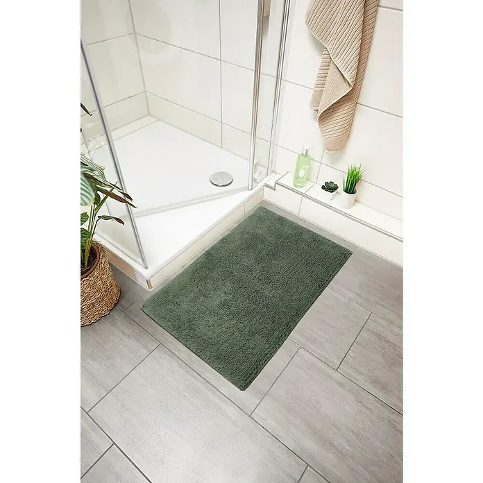 Badteppich Ibiza - 60 x 100 cm, Grün, 100% Baumwolle - Die dunkelgrüne Badematte sorgt für einen Farbtupfer im Badezimmer und bietet Komfort. Die Badematte liegt vor der Dusche auf den grauen Fliesen.