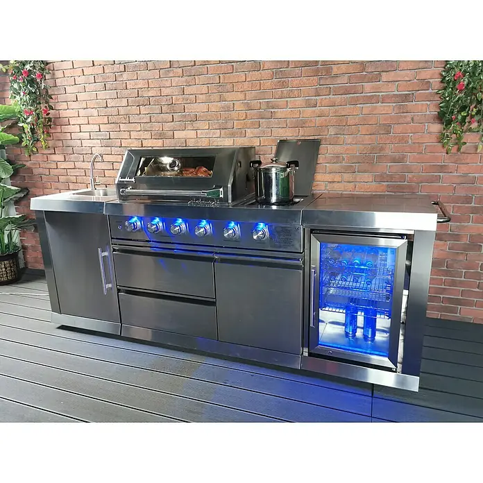 Buschbeck Outdoorküche Oxford - Edelstahl, Anzahl Brenner: 4 - Bild eines modernen Outdoor-Küchengrills aus Edelstahl mit Spüle, Grill, Kochfeld und Kühlschrank mit blauer Beleuchtung.