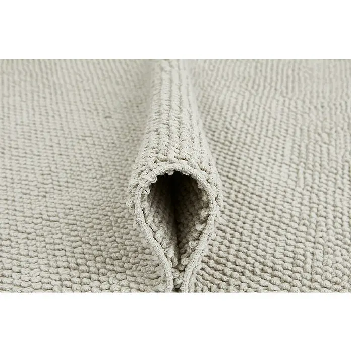 Badteppich Atlanta - 60 x 100 cm, 100% Baumwolle - Nahaufnahme einer hellen, gerollten Badematte mit weicher Textur, die Komfort und Saugfähigkeit verspricht.