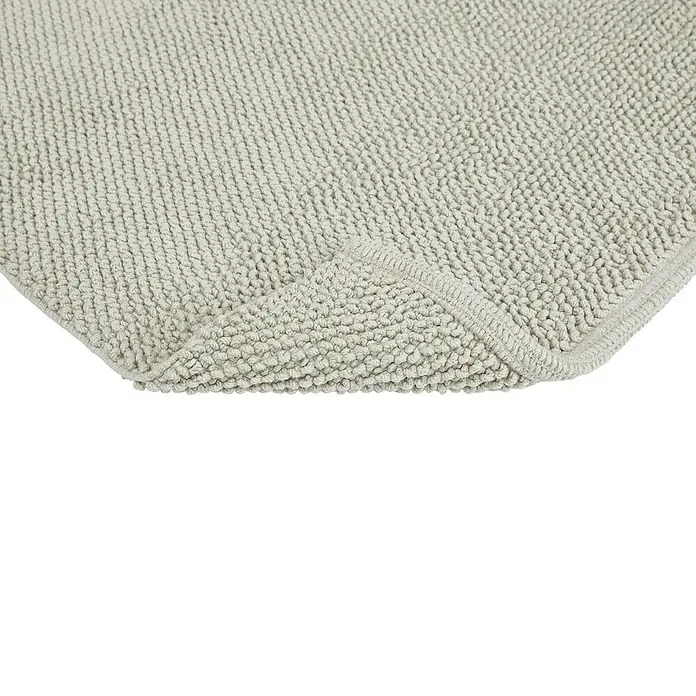 Badteppich Atlanta - 60 x 100 cm, 100% Baumwolle - Detailaufnahme einer weichen, hellgrauen Badematte mit gewebter Textur und umgeschlagener Ecke.