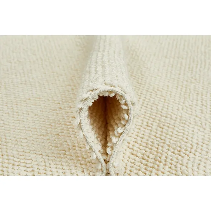 Badteppich Atlanta - 60 x 100 cm, Weiß, 100% Baumwolle - Detailaufnahme eines cremefarbenen Badteppichs mit gewebter Textur und einer dekorativen Falte. Weiche, luxuriöse Badematte.