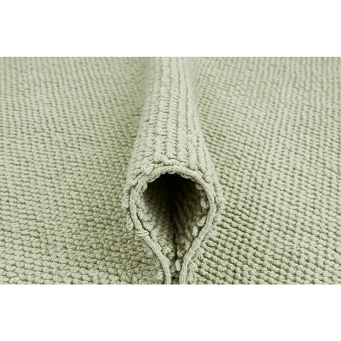 Badteppich Atlanta - 60 x 100 cm, Salbei, 100% Baumwolle - Detailaufnahme einer hellgrünen Badematte mit gerolltem Rand, die die Textur und Weichheit des Materials hervorhebt.\n