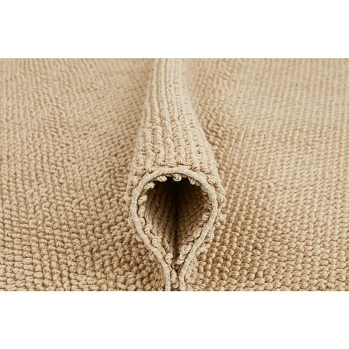 Badteppich Atlanta - 60 x 100 cm, Beige, 100% Baumwolle - Nahaufnahme eines beigen Badteppichs mit einer gefalteten Ecke, der die Textur und Weichheit des Materials hervorhebt.