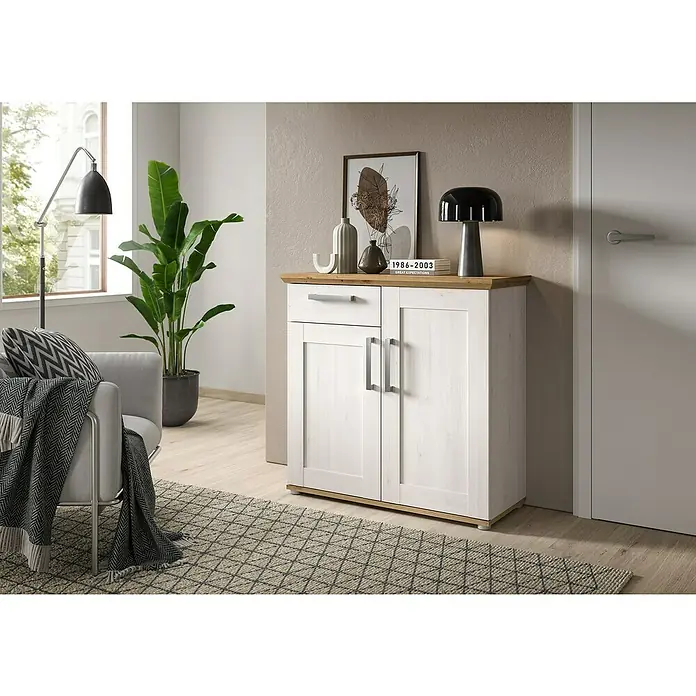 xonox.home Kommode - L x B x H: 39 x 90 x 88 cm, Weiß/Lärche, Anzahl Schubladen: 1 Stk. - Ein weißes Sideboard mit Schublade und zwei Türen, mit einer Dekoration und Lampe oben drauf, steht auf einem gemusterten Teppich.