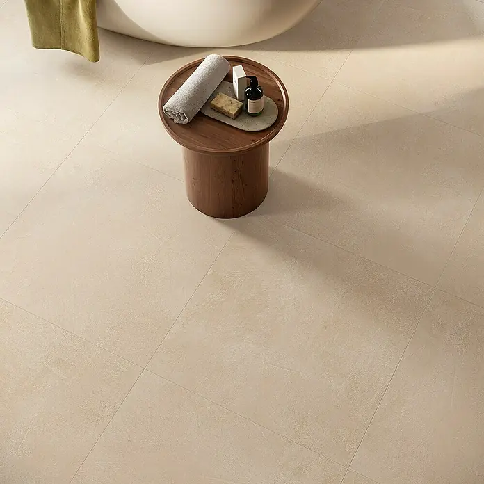 Atlas Concorde Solution Feinsteinzeugfliese Lexington - 80 x 80 cm, Lilium, Matt - Detailaufnahme eines Badezimmers mit beigen Bodenfliesen, einem kleinen Holztisch und Badutensilien.