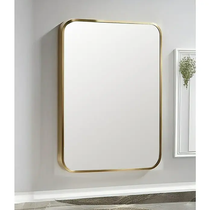 Espejo de pared Ovalado Zen - 60 x 100 cm, Oro - Un espejo rectangular con esquinas redondeadas y un marco dorado cuelga en una pared gris clara. El diseño moderno complementa baños y pasillos.