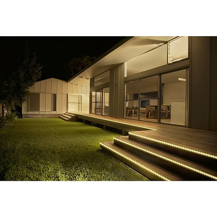 Osram Smart+ LED-Band Flex außen - Länge: 300 cm, Lichtfarbe: RGBW, 12,5 W, 740 lm, 220 V - 240 V - Moderne Hausfassade mit LED-Beleuchtung an den Stufen und entlang der Terrasse, die eine warme und einladende Atmosphäre schafft.