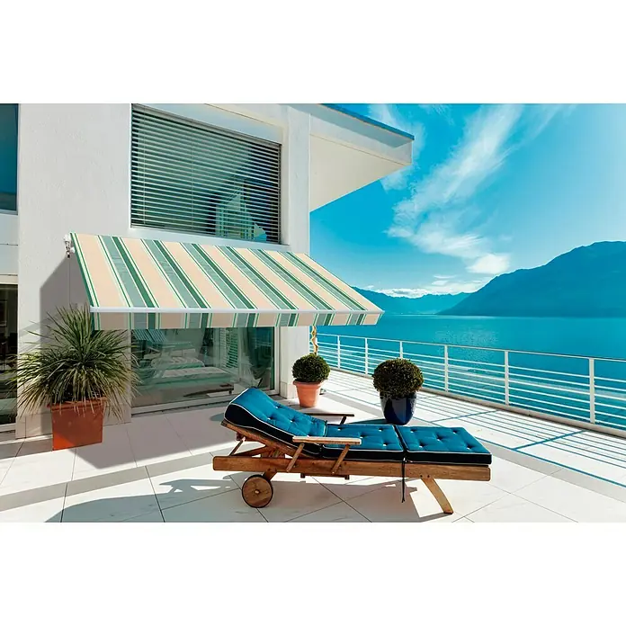 SmartSun Toldo de brazos extensibles Original Kit Acrílico - Beige/Verde, Ancho: 4 m, Caída: 2,5 m - Un toldo de rayas da sombra a un patio con una tumbona y vistas al océano.