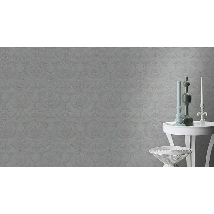 Rasch Trianon Vliestapete II - Dunkelgrau, Ornament, 10,05 x 0,53 m - Elegante graue Tapete mit filigranem Muster, kombiniert mit stilvollen Dekorationen auf einem weißen Beistelltisch.