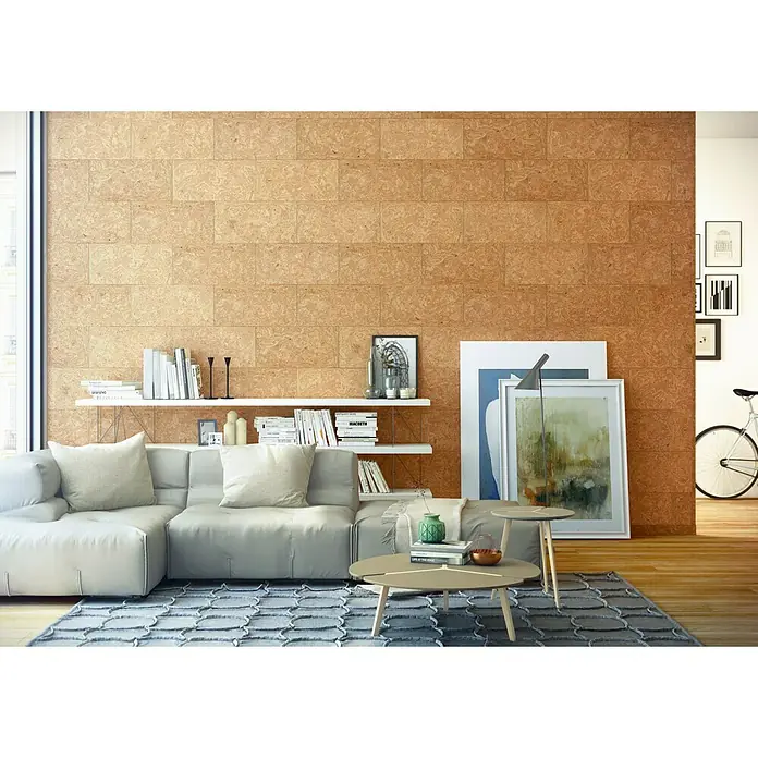 Bariperfil Perfil de acabado angular Corcho - 2,6 m x 3 cm - Salón con sofá modular, mesa de centro y estanterías frente a una pared de baldosas de corcho para una estética cálida y natural.