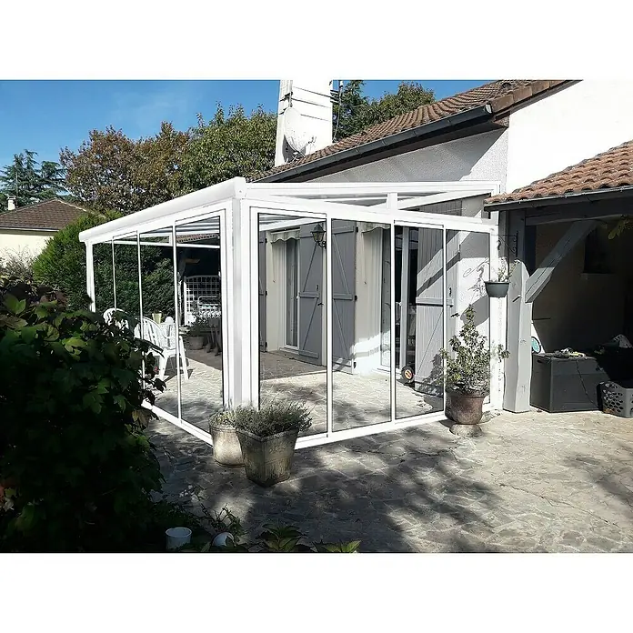 Wismar-NFI Wintergarten - 404 x 303,3 cm, Pultdach, Polycarbonat, Reinweiß, Milchig Weiß - Außenansicht einer modernen, weißen Terrassenüberdachung mit Glaselementen, die einen stilvollen Übergang zum Garten bietet.