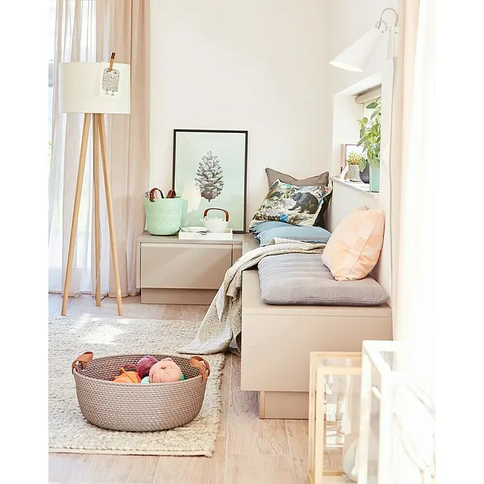 SCHÖNER WOHNEN-Farbe Wandfarbe Trendfarbe - Pearl, Matt, 2,5 l, Konservierungsmittelfrei - Ein gemütliches Interieur mit einem Korb voller Wolle auf einem Teppich, einem bequemen Sitzbereich mit Kissen und einer Stehlampe.