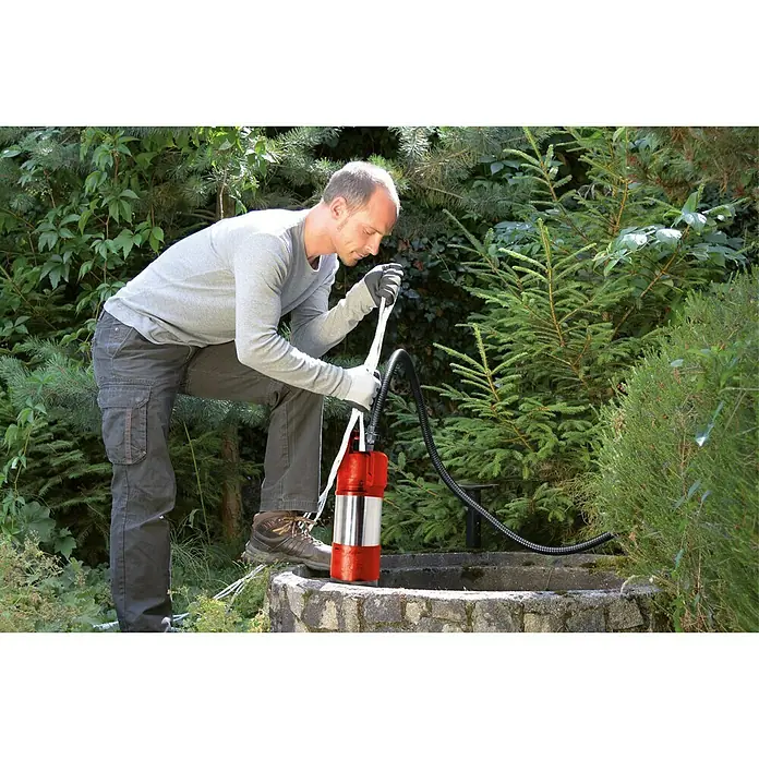 Einhell Drucktauchpumpe GE-PP 1100 N-A - 1.100 W, Max. Fördermenge: 6.000 l/h - Eine Tauchpumpe wird von einem Mann in einem Garten in einen Brunnen gelassen, um Wasser abzupumpen.