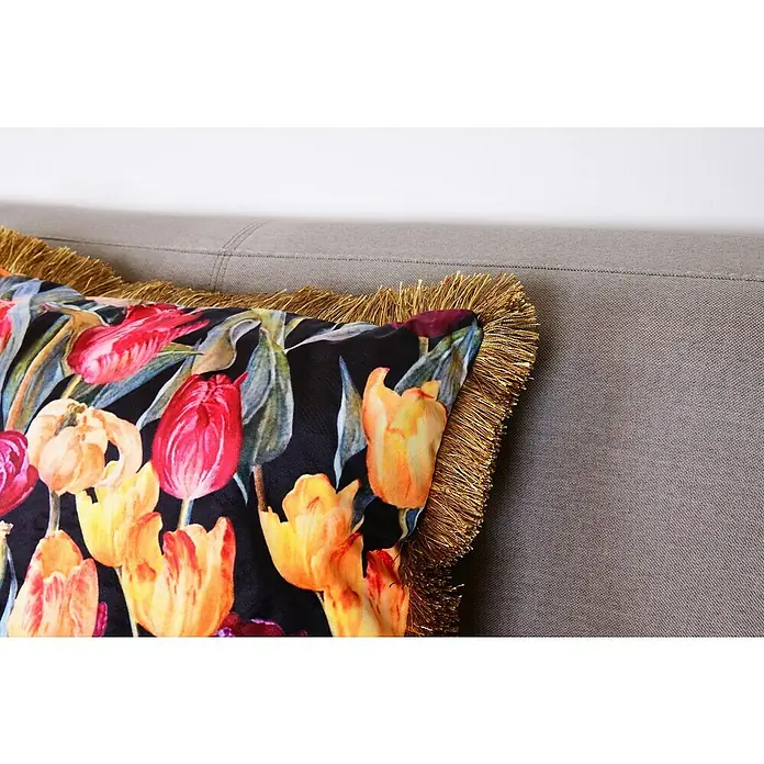 Kissen Elona - Blumen, 45 x 45 cm, 100 % Polyester - Nahaufnahme eines dekorativen Kissens mit Tulpenmuster und goldenen Fransen auf einem grauen Sofa.