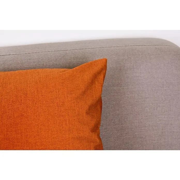 Kissen Finn - Orange, 45 x 45 cm, 100 % Polyester - Nahaufnahme eines orangefarbenen Sofakissens vor einem grauen Sofa, das die Textur und die Farben der Stoffe hervorhebt.
