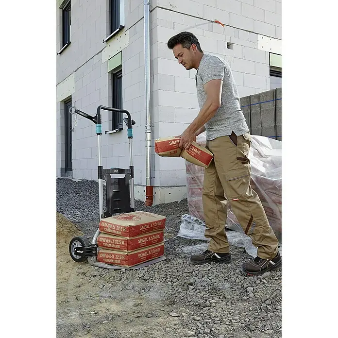 Wolfcraft Carretilla de mano TS 1500 - Capacidad de carga: 200 kg - Un hombre carga un carretilla Wolfcraft con varios sacos de cemento Seibel & Söhne frente a una casa en construcción.
