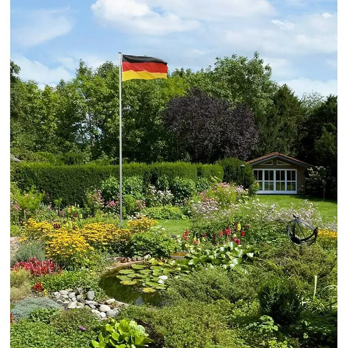 Fahnenmast - Höhe: 6,2 m, Aluminium - Flagge Deutschlands weht stolz über einem üppigen Garten mit Teich und Blumen, ein idyllisches Landschaftsbild.