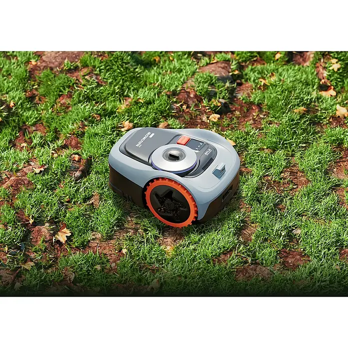 Segway Mähroboter Navimow I208E AWD - 800 m², Schnittbreite: 18 cm, Satellitengestützte Navigation, GPS - Ein Navimow-Mähroboter steht auf einem Rasen mit Blättern. Der Rasenroboter hat orangefarbene Räder und eine graue Karosserie mit Bedienelementen.