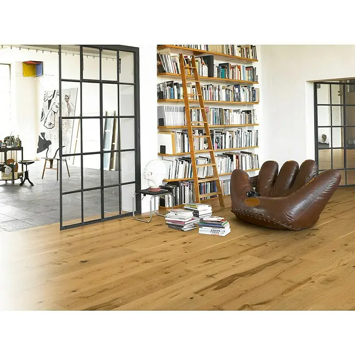 Parador Parkett Basic 11.5 - Modern Oak Rustikal, Landhausdiele, 2.200 x 185 x 11,5 mm - Helle, strukturierte Holzböden verleihen diesem einladenden Wohnzimmer mit Bücherregal und Ledersessel einen natürlichen und warmen Touch.