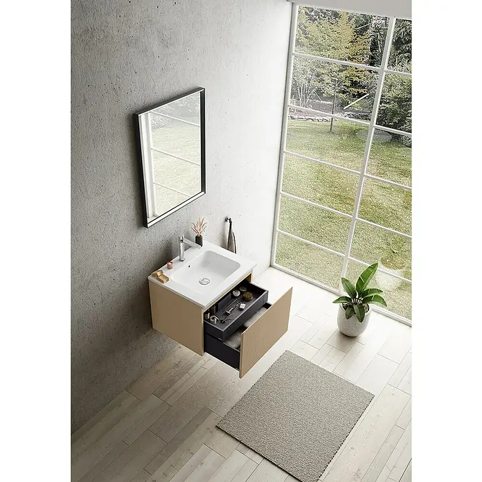 Camargue Pura Waschtischunterschrank - B x T x H: 59 x 50 x 46 cm, Rovere Cera - Ein modernes Badezimmer mit einem Hängeunterschrank in Beige mit offenem Schubfach, Waschbecken, Spiegel und einem Fenster mit Blick ins Grüne.