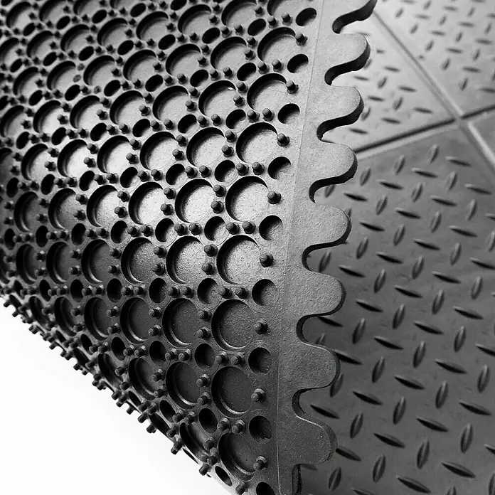 Floordirekt Bodenschutzmatte Puzzle Gummiläufer - 92 x 92 cm, Schwarz - Nahaufnahme einer rutschfesten, schwarzen Gummimatte mit Noppen und Löchern für den gewerblichen Gebrauch.