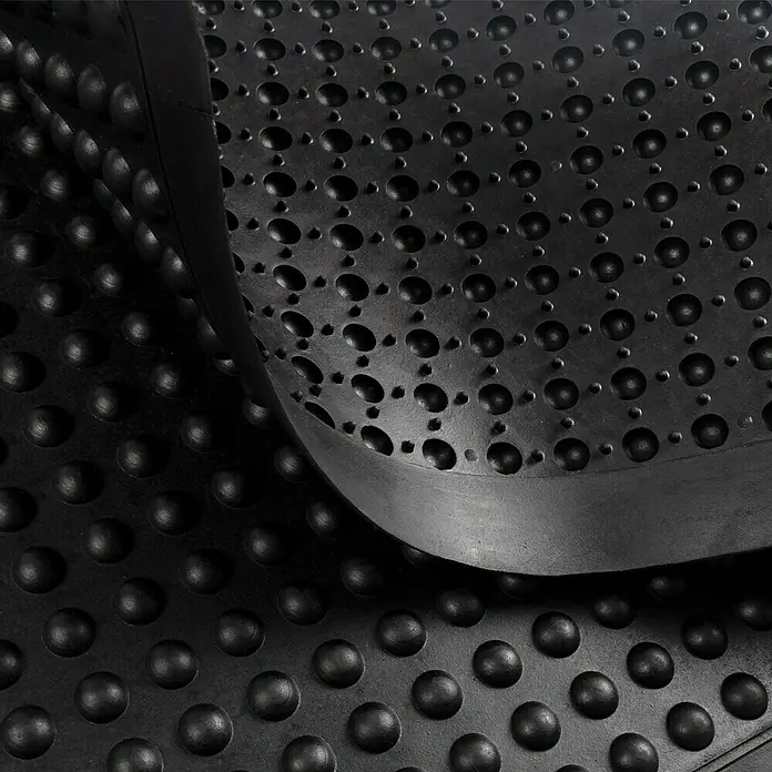 Floordirekt Bodenschutzmatte Bubble - Schwarz, 90 x 60 cm - Nahaufnahme einer schwarzen Anti-Ermüdungsmatte mit Noppen und Löchern für Komfort und Sicherheit am Arbeitsplatz.