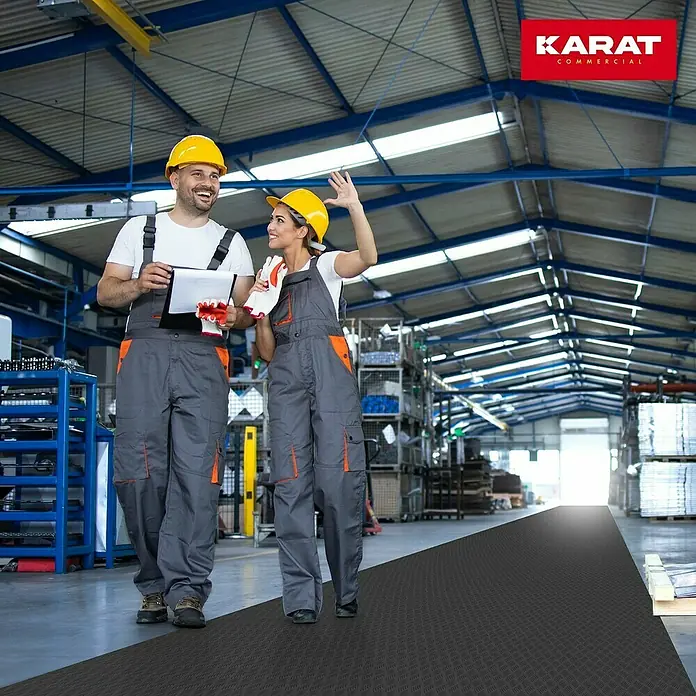Floordirekt Läufer Diamond Cut - 120 x 250 cm, Schwarz - Zwei Arbeiter inspizieren eine robuste Karat Commercial Antirutschmatte in einer Lagerhalle und sorgen für Sicherheit.