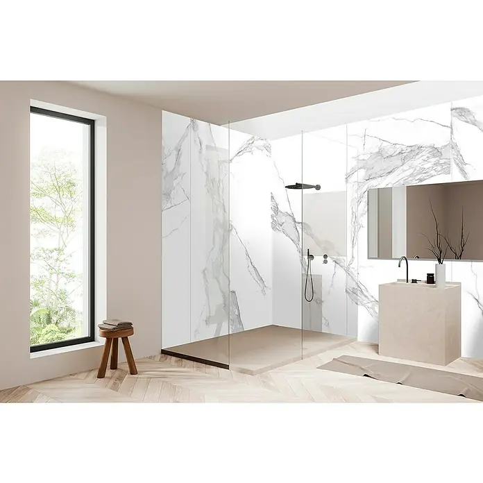 Bariperfil Panel de pared Corewall Carrara - 258 x 102,3 cm, Blanco - Elegante baño con paredes de mármol, ducha a ras de suelo y suelo de madera. El tocador y el taburete de materiales naturales complementan el diseño.